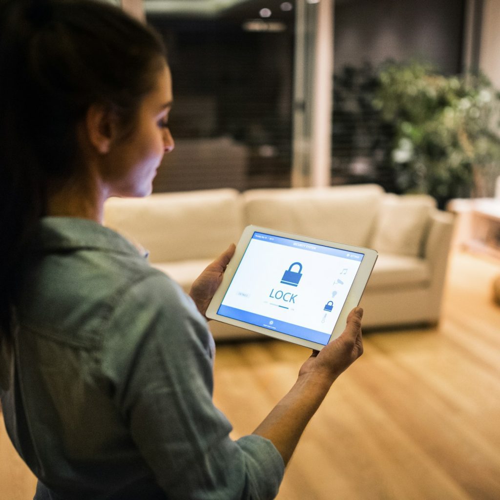 A woman holding a tablet with smart home screen.