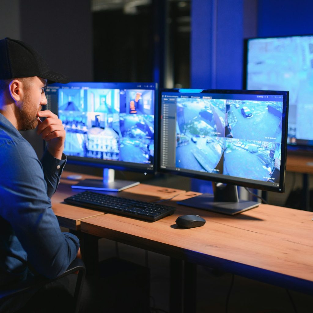 Male security guard monitoring modern CCTV cameras indoors